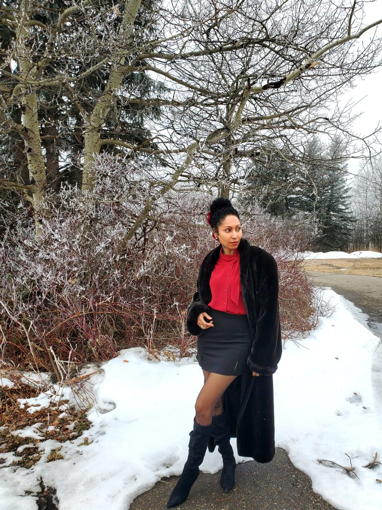 Exuding opulence, a woman adorns herself in a vintage faux fur jacket, gracefully paired with a classic blouse and a sleek black mini skirt. A true embodiment of timeless elegance.