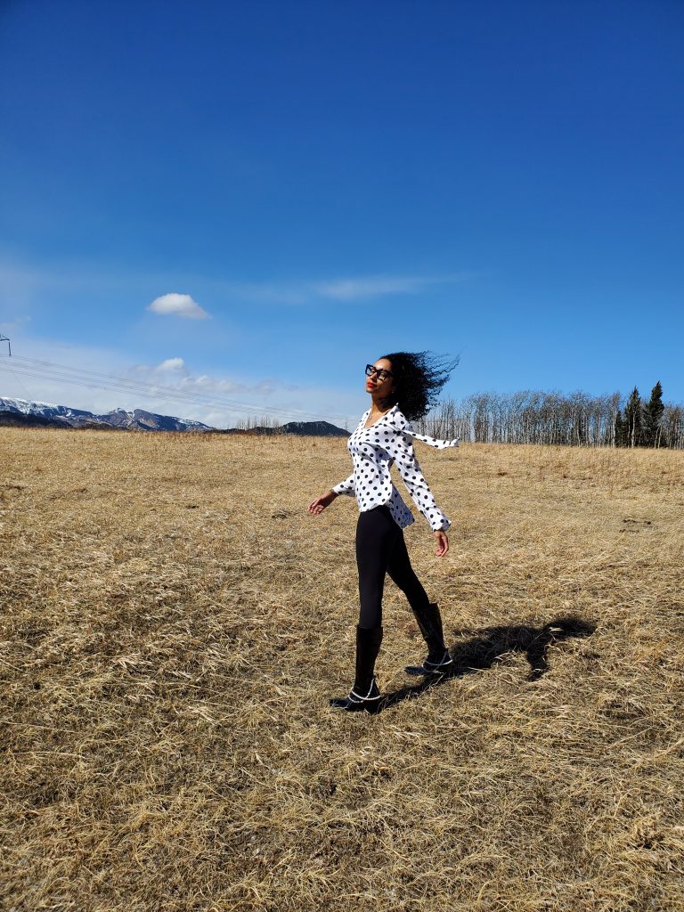 Exuding sophistication, a woman strikes a pose in a stunning color blocked black and white blouse paired with sleek leggings. Her ensemble is elevated by fashionable PVC ankle boots.