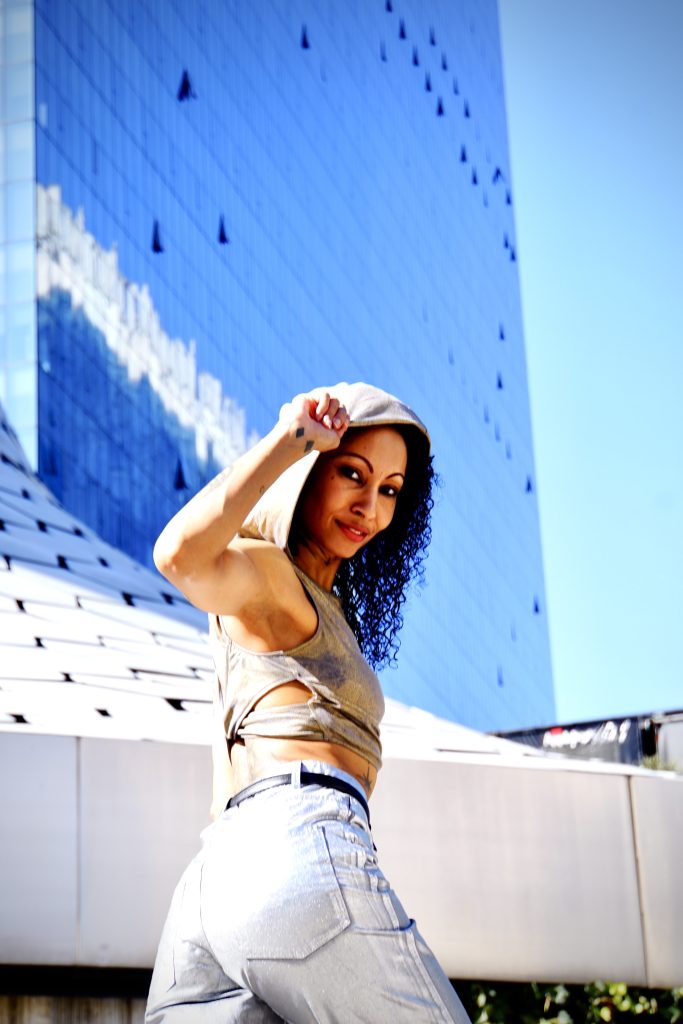 With an air of sophistication, a fashion-forward woman showcases her impeccable style in metallic silver pants, standing gracefully in front of a magnificent museum.