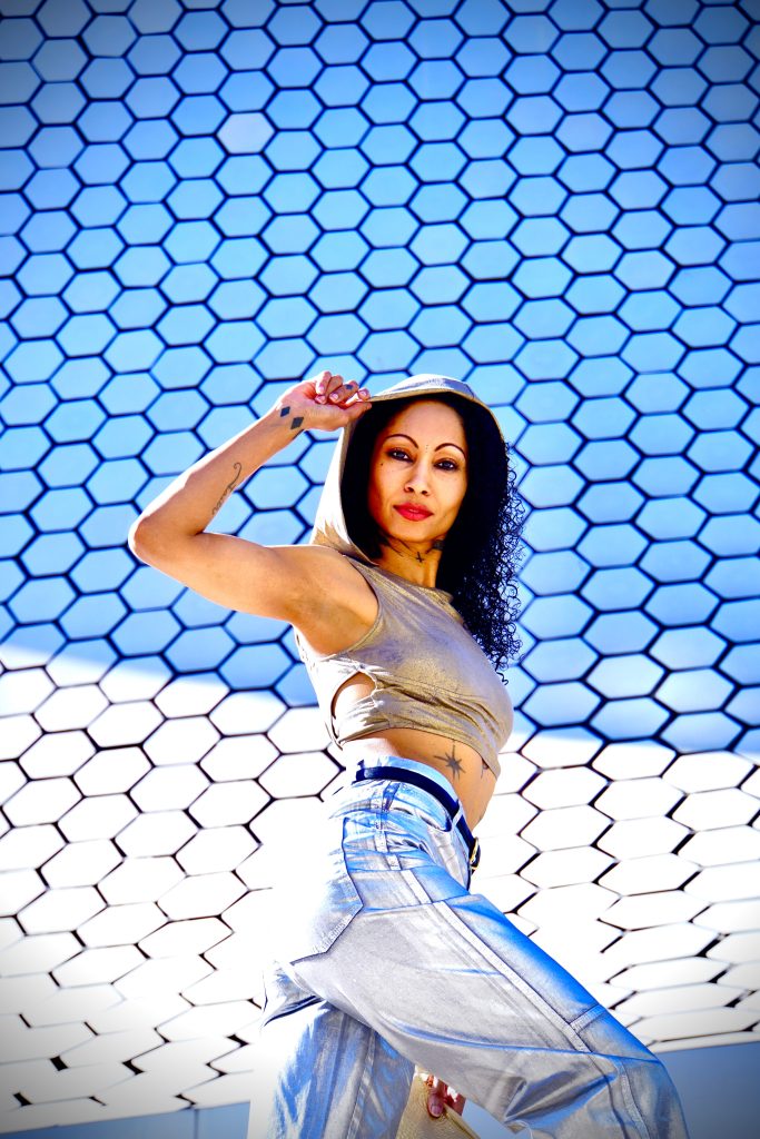 A glamorous woman, donning metallic silver pants, strikes a pose in front of a majestic museum