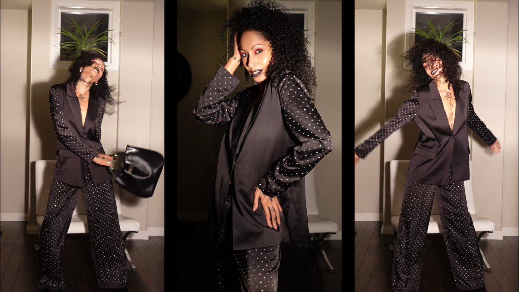 A fashionable woman showcasing her tattoos in a sophisticated black suit, radiating power and style.