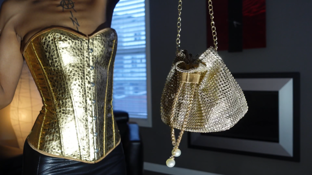  Mesmerizing in her opulent gold corset, a woman exudes grace and confidence as she poses effortlessly, captivating the camera with her radiant beauty.